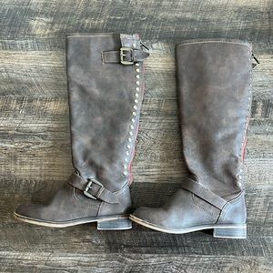 Tall brown boots with red and gold stud accents.